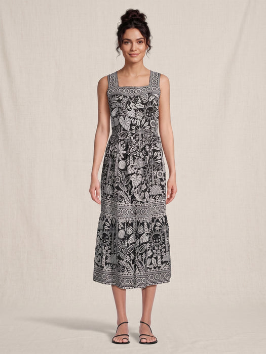 Woman wearing a black and white tropical patterned midi dress with square neck and  wide tank straps from Johnny Was