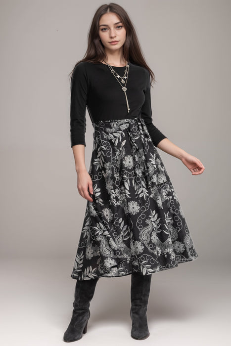 Woman wearing a midi dress with solid black bodice and floral printed wrap skirt