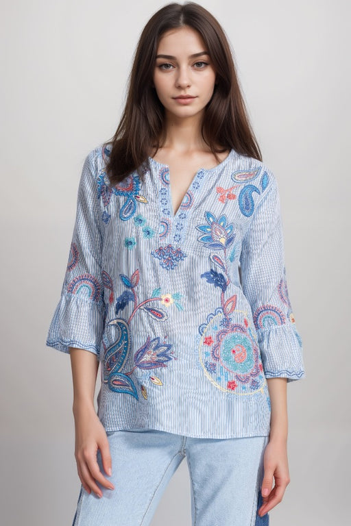 Woman wearing a blue stripe silk blouse with paisley embroidery and ruffle sleeves