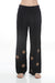 Woman wearing a black wide leg pleated pants with embroidery from Johnny Was