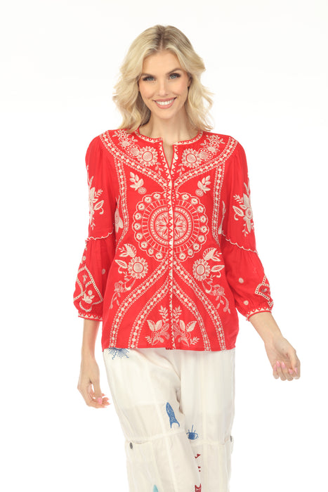 Woman wearing a red embroidered blouse with intricate patterns and button front from Johnny Was