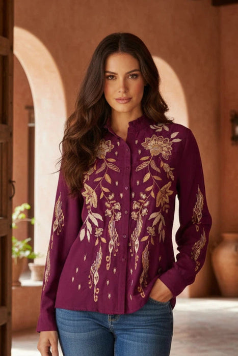 Woman wearing a plum-colored long sleeve blouse with gold floral embroidery from Johnny Was