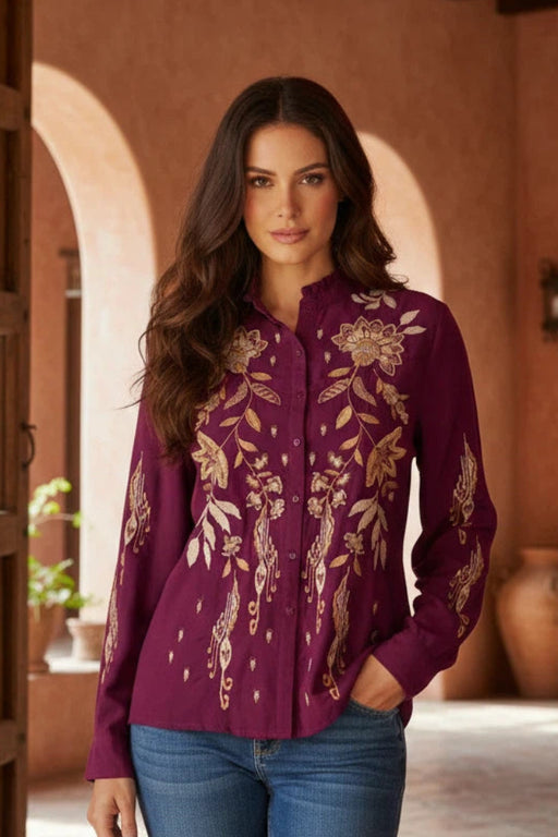 Woman wearing a plum-colored long sleeve blouse with gold floral embroidery from Johnny Was