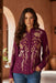Woman wearing a plum-colored long sleeve blouse with gold floral embroidery from Johnny Was