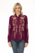 Woman wearing a plum-colored long sleeve blouse with gold floral embroidery from Johnny Was
