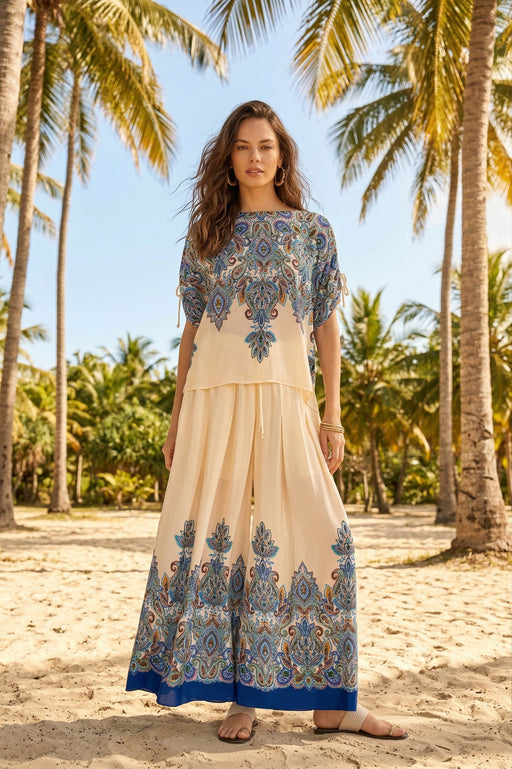 Woman wearing a colorful paisley patterned top with boat neck and ruched dolman sleeves from Johnny Was