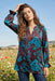 Woman wearing a two-tone floral printed tunic top with v-neck and long sleeves from Johnny Was