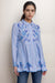 Woman wearing a blue embroidered shirt tunic with button down closure from Johnny Was