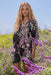 Woman wearing a black tiered dress with floral paisley print and 3/4 sleeves from Johnny Was