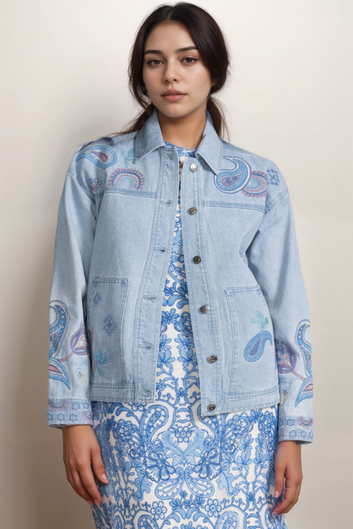 Woman wearing a light blue denim jacket with paisley embroidered patterns from Johnny Was
