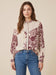 Woman wearing a beige long sleeves top with contrasting florals over plaid pattern from Johnny Was