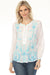 Woman wearing a white henley long sleeve blouse with blue floral embroidery from Johnny Was