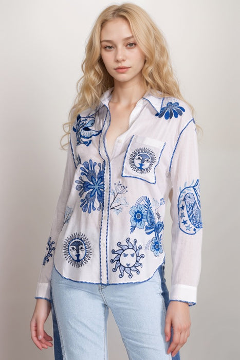 Woman wearing a white shirt with blue embroidery and chest pocket