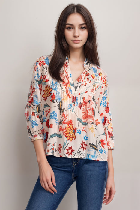 Woman wearing a silk blouse with colorful floral print, pintuck, and ruffle detail on the 3/4 sleeves