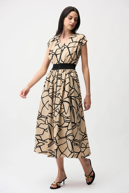 Model wearing Joseph Ribkoff beige and black seersucker abstract print fit and flare dress with cap sleeves, front zip detail, and cinched waist for a flattering silhouette.