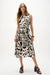 Woman wearing Joseph Ribkoff beige multi tropical print fit and flare wrap dress, featuring a sleeveless design, tie waist, lightweight gauze fabric, and a flowy feminine silhouette.