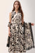 Woman wearing a two-tone scarf in beige and black with tropical print and fringe edges from Joseph Ribkoff