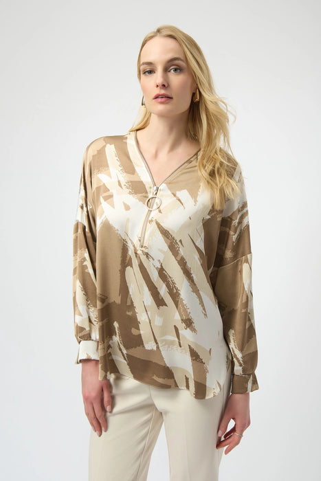 Woman wearing a beige and off-white abstract patterned blouse with zip v-neck and long sleeves