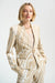 Woman wearing a beige and vanilla abstract print fitted jacket with button closure, styled with matching trousers and a neutral top.