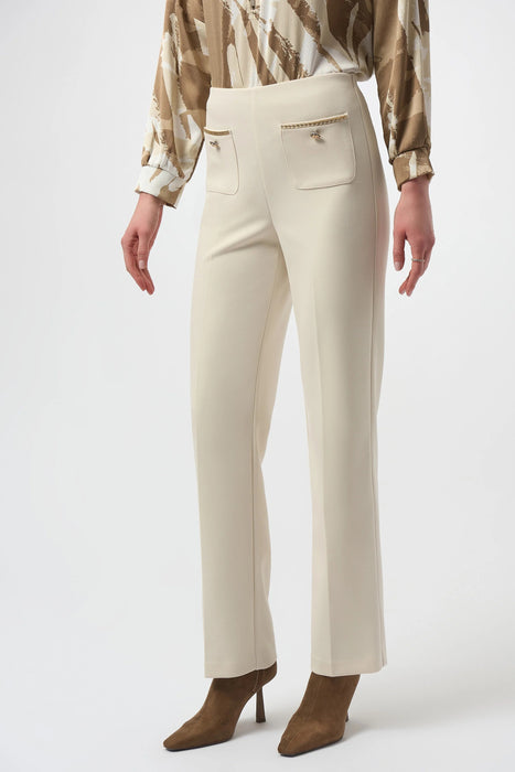 Woman wearing a beige pant with gold chain and button accent at the front pockets