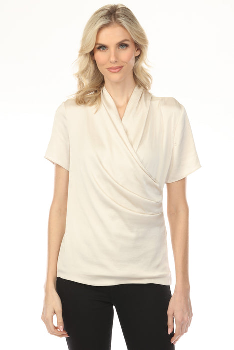 Woman wearing a cream-colored faux wrap top with ruching at the waist and short sleeves from Joseph Ribkoff