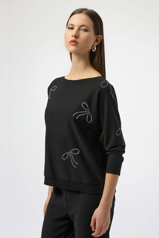 Woman wearing a black sweater top with iron-on bow embellishment and 3/4 sleeves from Joseph Ribkoff