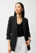 Woman wearing a black boxy blazer with shirred three-quarter sleeves and notched lapel, styled for office wear, business meetings, travel, or elegant evening outings.