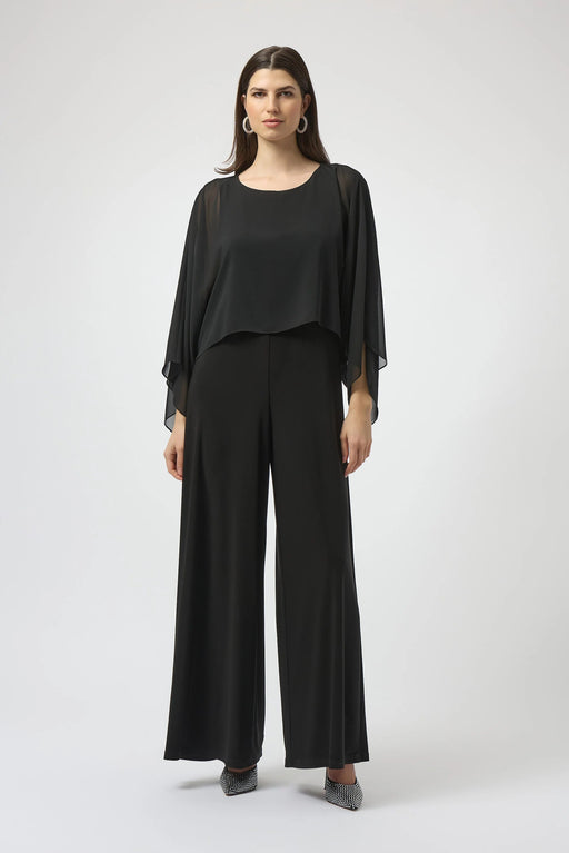 Woman wearing a black one-piece jumpsuit with lightweight chiffon overlay and wide leg from Joseph Ribkoff
