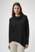 Woman wearing a solid color black sweater knit top with cowl neck and asymmetric hem