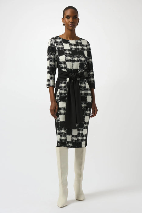 Woman wearing a black and white checkered dress with a waist sash from Joseph Ribkoff