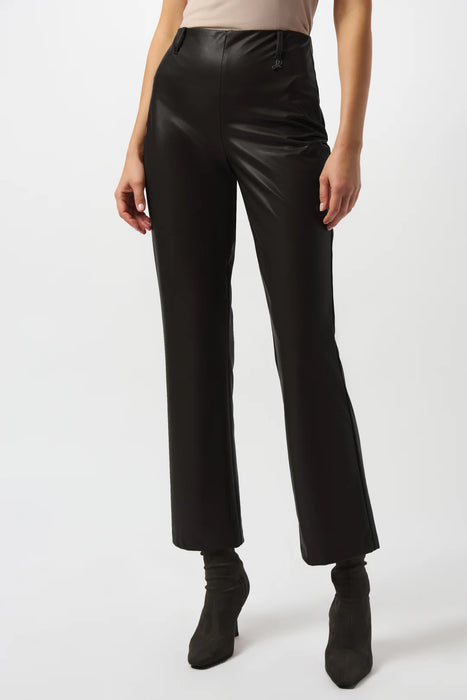 Woman wearing a solid color black leatherette pant with belt loops and ornament