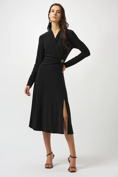 Woman wearing a black silky knit fit and flare dress chain detail on the waist and wrap v-neck