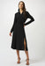 Woman wearing a black silky knit fit and flare dress chain detail on the waist and wrap v-neck
