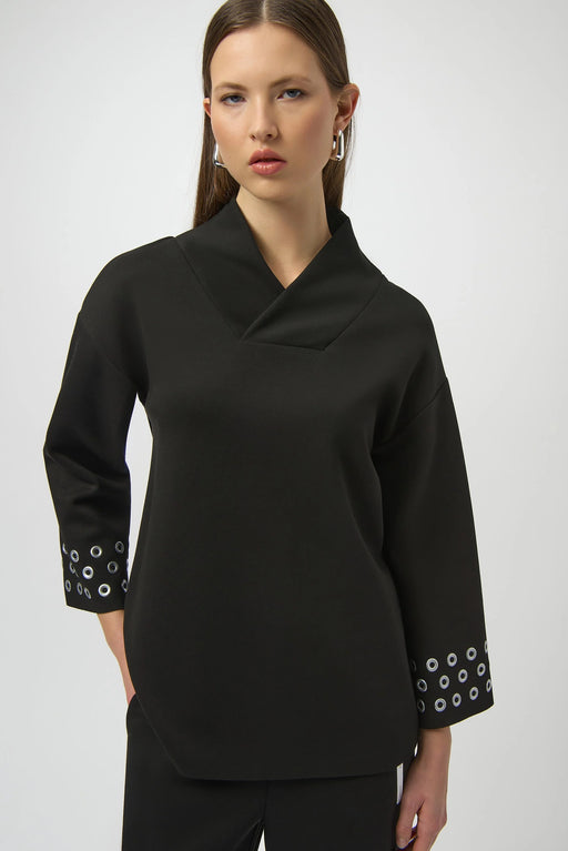Woman wearing a black top with grommet detailed cuffs and wrap v-neck from Joseph Ribkoff