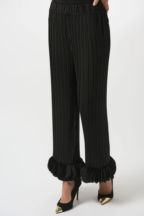 Woman wearing a black lightweight pleated wide leg pant with circle appliqués at the hem