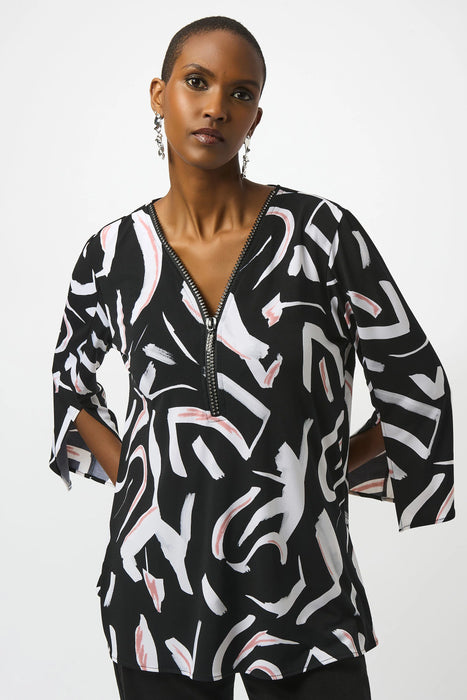 Woman wearing a patterned tunic top with rhinestone embellished zip v-neck