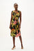 Woman wearing a black tropical floral print wrap dress with sleeveless V-neck design and waist buckle detail, styled for summer elegance.