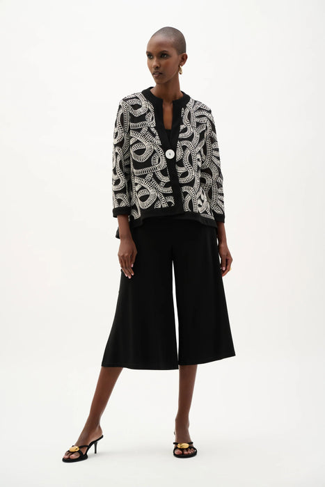 Woman wearing Joseph Ribkoff abstract print swing jacket in black and white, featuring bold patterned design, contrast trim, single-button closure, and elegant lightweight layering style.