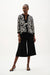 Woman wearing Joseph Ribkoff abstract print swing jacket in black and white, featuring bold patterned design, contrast trim, single-button closure, and elegant lightweight layering style.