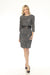 Woman wearing a black and white tweed sheath dress with faux leather waist detail and metal chain accent from Joseph Ribkoff