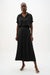Woman wearing a black Joseph Ribkoff pull-on culotte pants with pleats, featuring flowy wide-leg silhouette, cropped length, and a flattering high-rise modern fit.