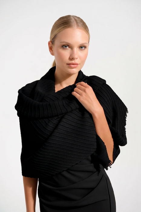 Woman wearing a black ribbed shrug over a black dress against a white background