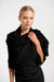 Woman wearing a black ribbed shrug over a black dress against a white background