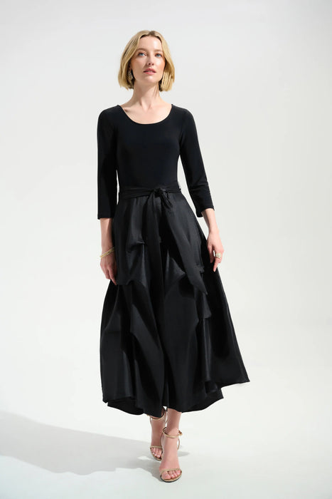 Woman wearing a black 3/4 sleeve dress with pleated midi taffeta skirt from Joseph Ribkoff