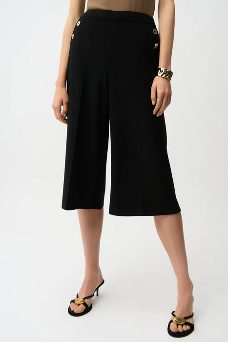 Woman wearing a black cropped wide leg pants with pull on elastic waist and side pockets from Joseph Ribkoff