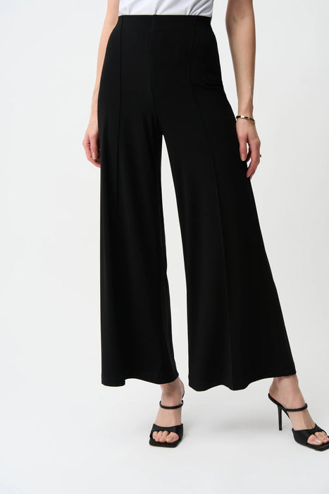 Woman wearing silky knit high-waist wide leg pants with front pintuck seams, styled for office wear, travel, business casual outfits, or contemporary chic fashion.