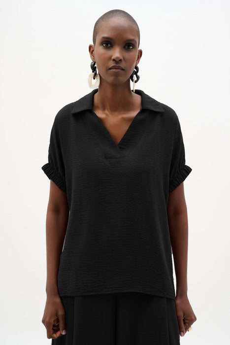 Woman wearing a black short sleeves top with collared v-neck from Joseph Ribkoff