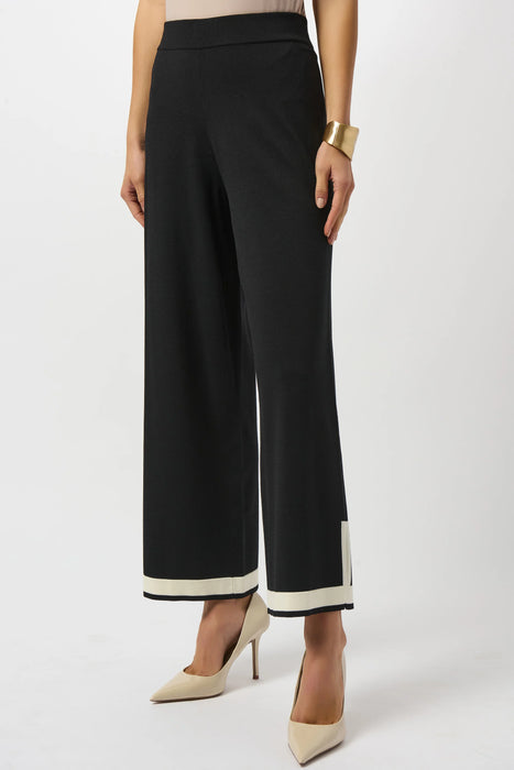 Woman wearing a black wide leg knit pant with contrast trim on the hem