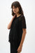 Woman wearing Joseph Ribkoff black viscose fringe sweater knit top styled for casual chic outings, resort wear, summer events, and relaxed evening looks.