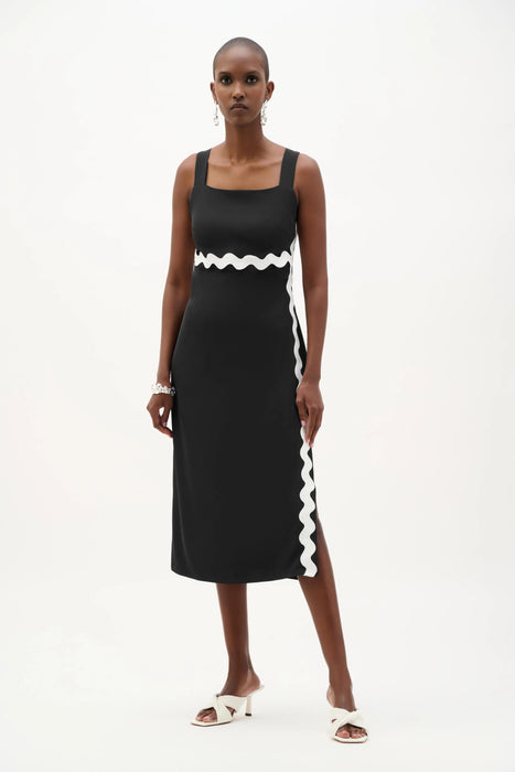 Woman wearing a black sleeveless midi dress with white contrast trim, square neck, and side slit from Joseph Ribkoff
